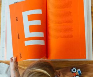 Child reading an orange book book-16@2x